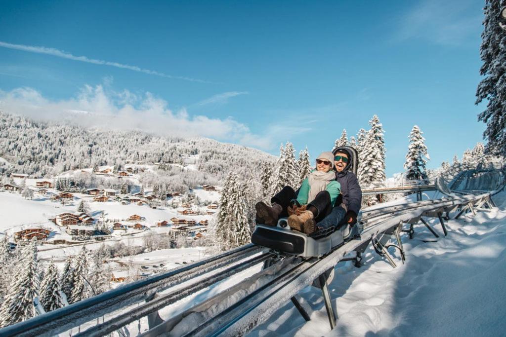 a couple riding on a ski lift in the snow at GESPERE LE STELLA in Les Gets