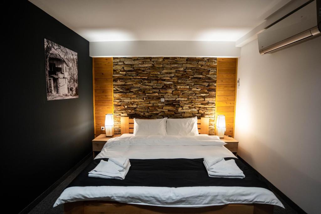 um quarto com uma cama grande e uma parede de tijolos em Velkov Apartments em Vinica