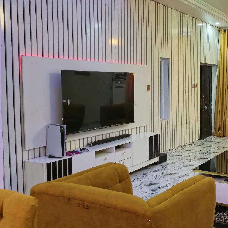 a living room with two chairs and a flat screen tv at S&A Lump Apartments, Enugu, Nigeria in Enugu