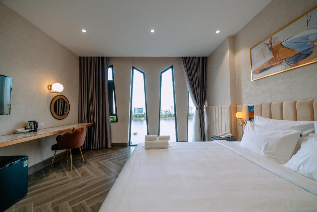 a hotel room with a large bed and windows at La Beaute Hotel - Quy Nhơn in Quy Nhon