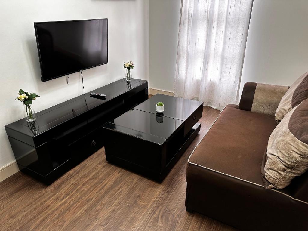 uma sala de estar com um sofá e uma televisão de ecrã plano em Nosu Modern Apartments Rivonia em Joanesburgo