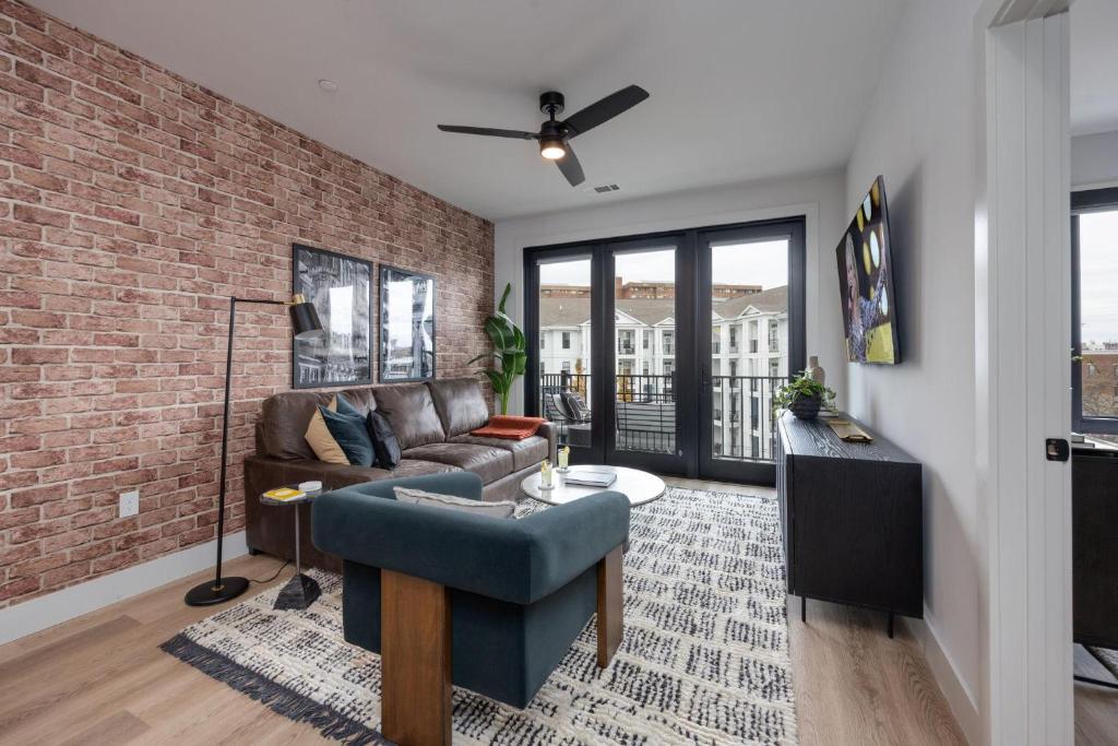a living room with a couch and a brick wall at Vesta - Odyssey - Heart of Midtown in Nashville