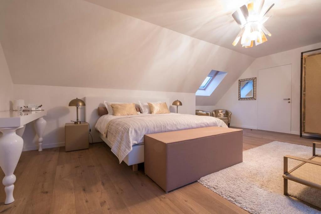 a white bedroom with a bed and a table at Familie &amp; Vriendenwoning met fantastisch uitzicht in Ellezelles