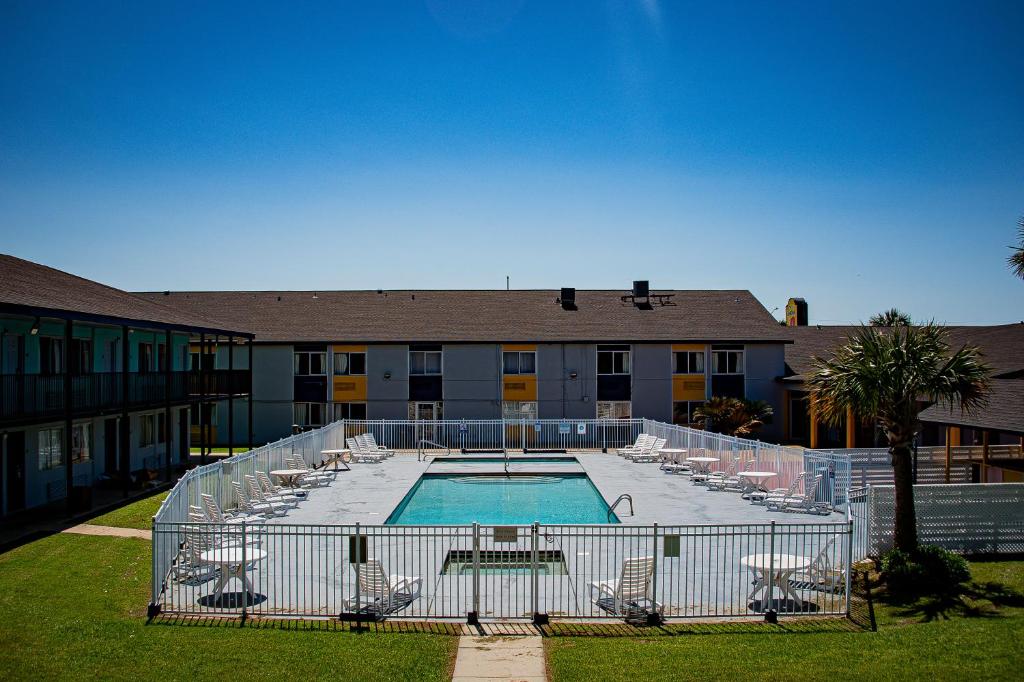 a swimming pool with chairs and a building at Super 8 by Wyndham Biloxi in Biloxi