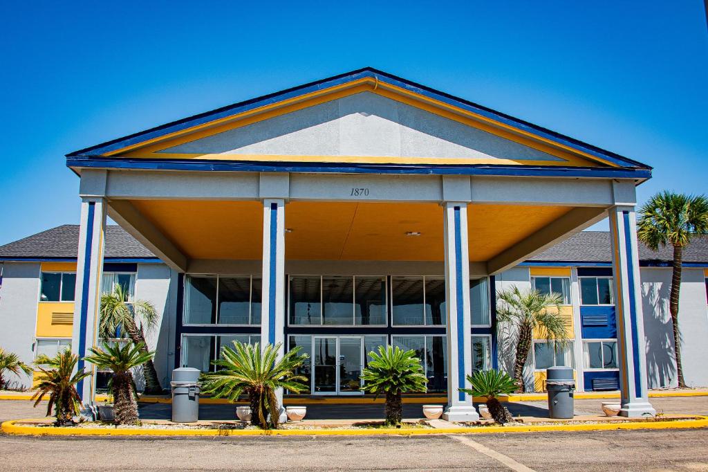 a building with palm trees in a parking lot at Super 8 by Wyndham Biloxi in Biloxi