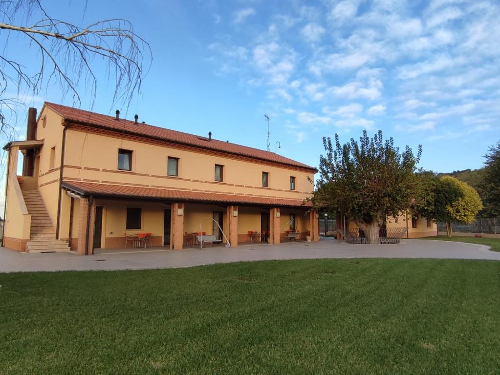 ein großes Gebäude mit einem Grasfeld davor in der Unterkunft Agriturismo La Buona Compagnia in Iesi