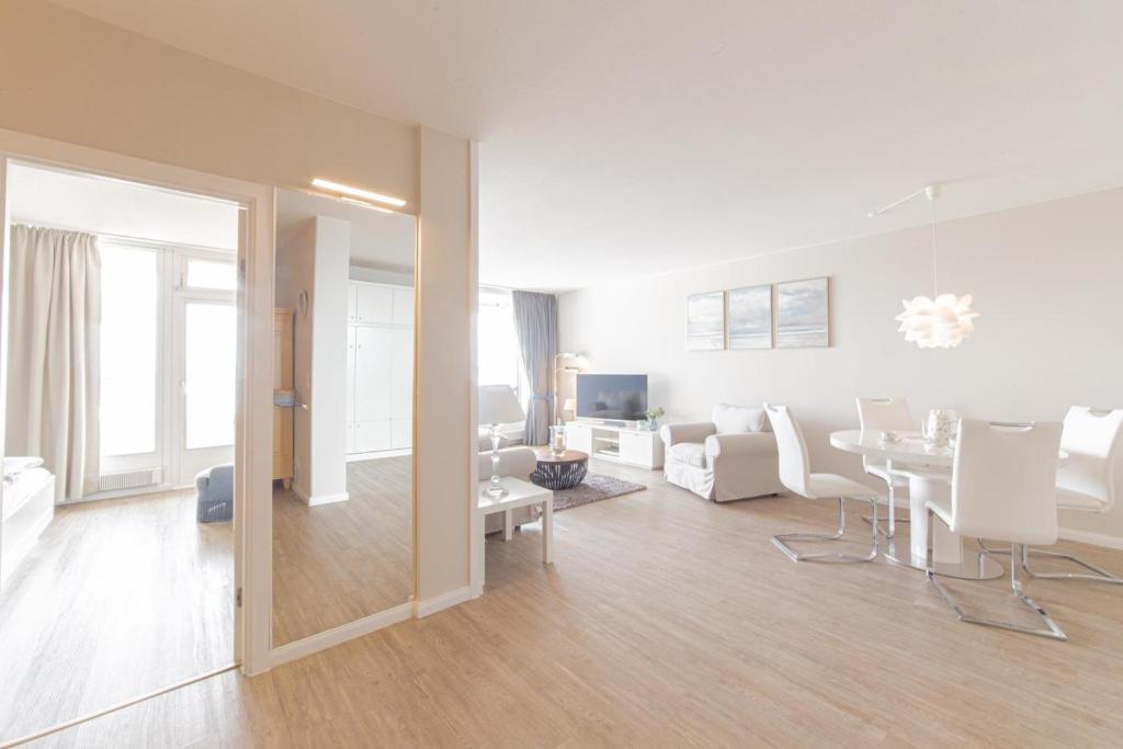 a living room with white furniture and a dining room at Ferienwohnung Residenz App. 911 in Timmendorfer Strand