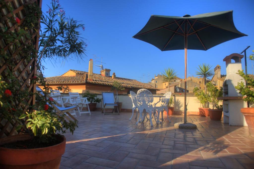 un patio con sombrilla, mesas y sillas en La Terrazza, en Tuscania