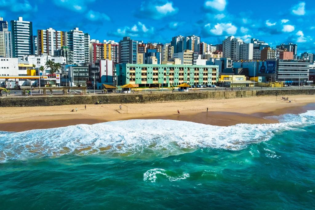 uitzicht op een strand met een stad op de achtergrond bij Hotel Verdemar in Salvador