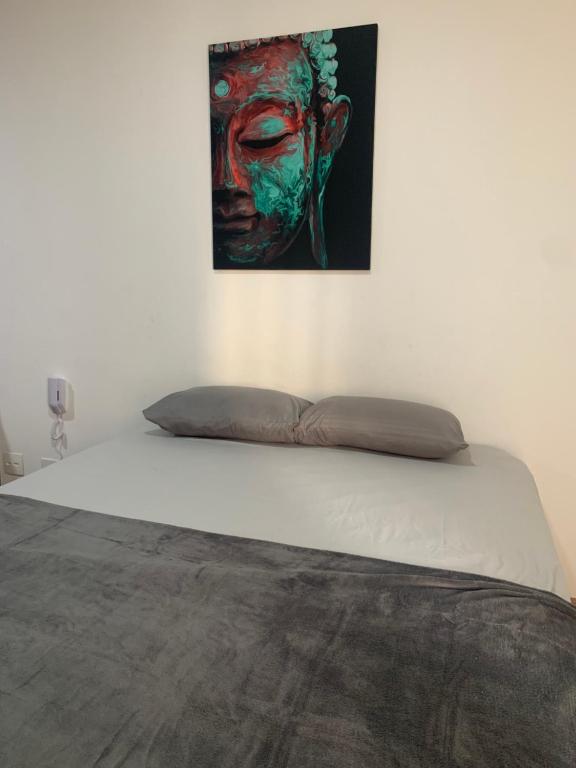 ein Bett mit einem Gemälde an der Wand in der Unterkunft Flat 406A com piscina in São Vicente