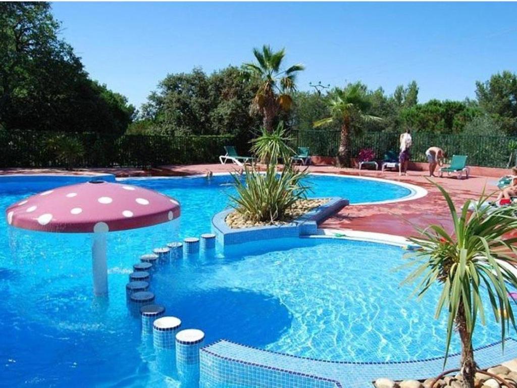 a swimming pool with an umbrella and a swimming pool at Chalet Agde, 3 pièces, 6 personnes - FR-1-607-59 in Agde