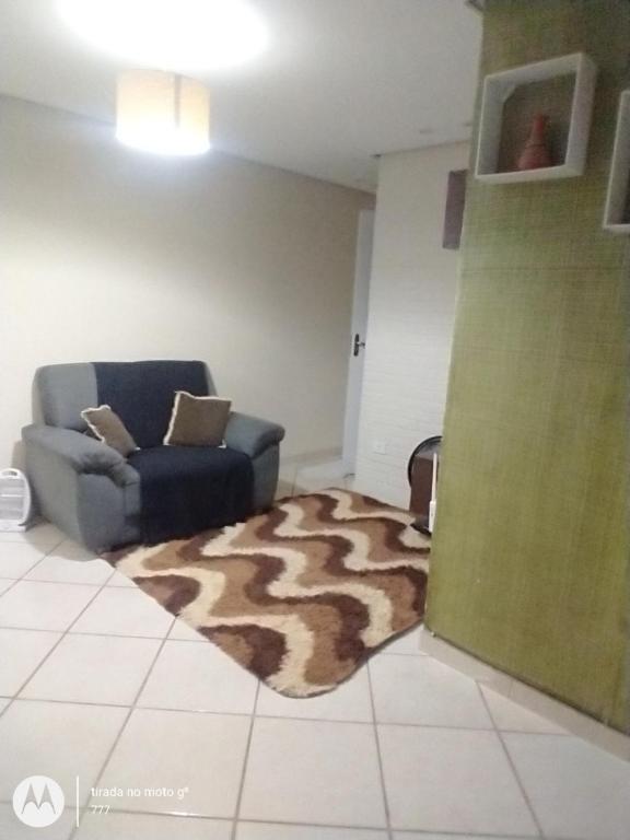 een woonkamer met een stoel en een tapijt bij Apartamento in São Lourenço