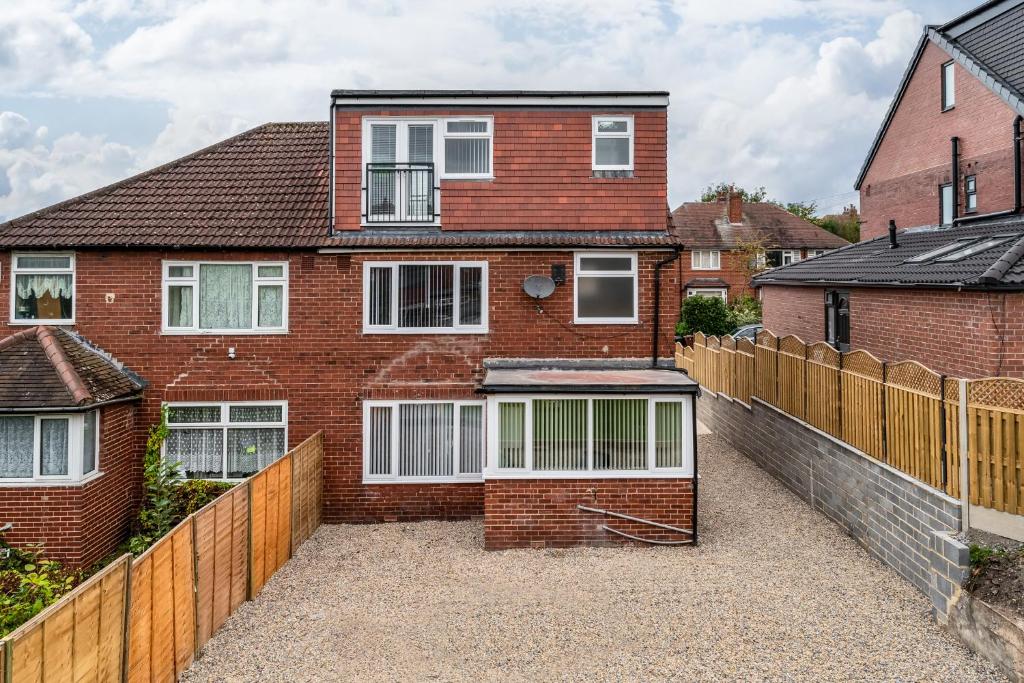 a brick house with a fence in front of it at Immaculate 5-Bed House in Leeds in Leeds