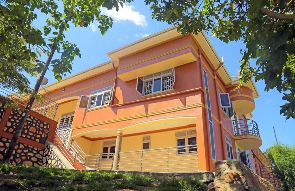 a yellow and orange building with a tree at Bigodi Community Lodge in Kamwenge