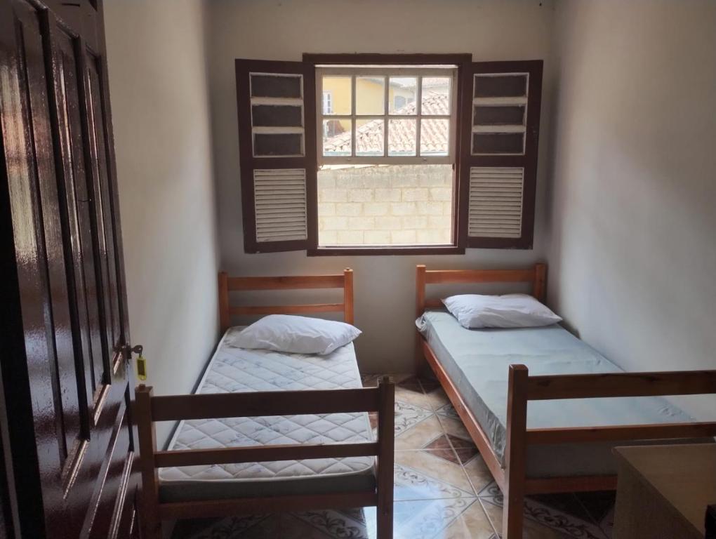 Duas camas num quarto com uma janela em Casa perto de tudo, pra você ter ótima experiência. Bora Conhecer Ouro Preto.... em Ouro Preto