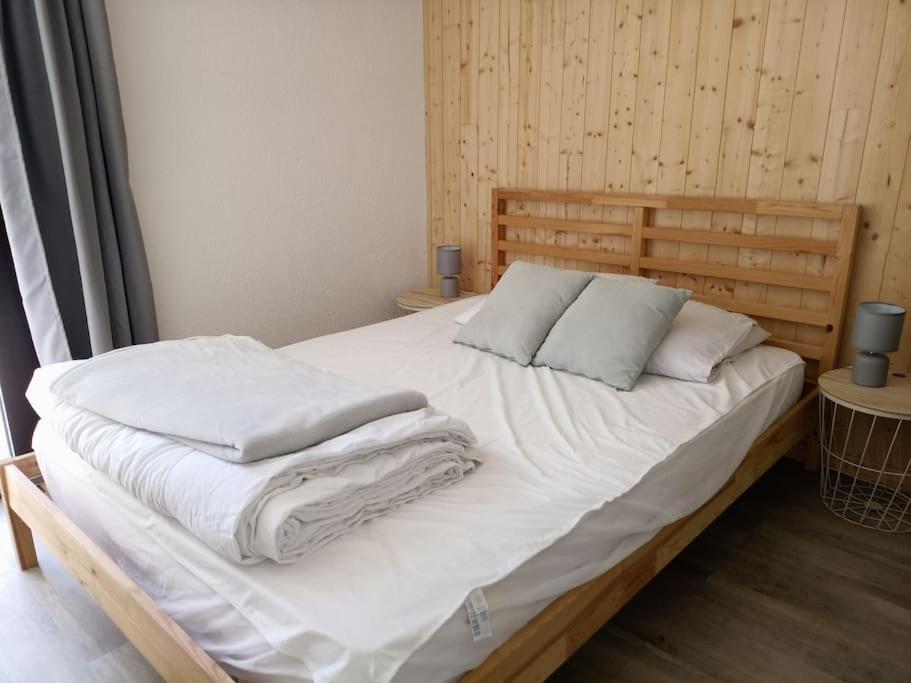 a large bed with white sheets and pillows on it at Appartement avec belle vue sur montagne in Égat