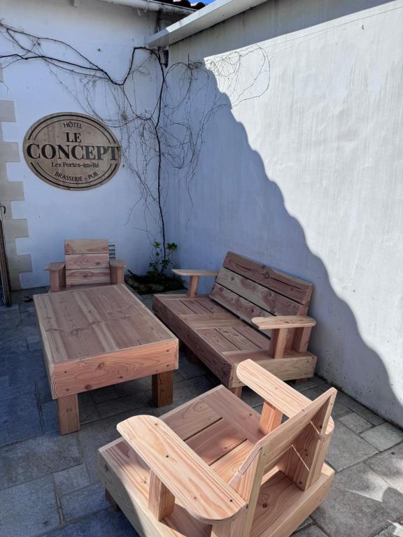 deux tables et bancs en bois devant un bâtiment dans l'établissement Le Concept Hotel, aux Portes