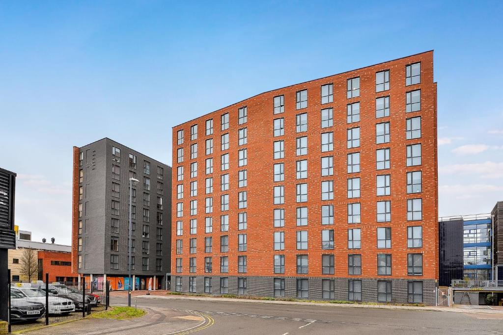 a large red brick building next to a parking lot at Exquisite Ensuites at The Croft Derby in Derby
