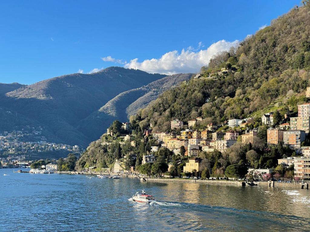 a boat in the water on a river with buildings at Lake Front View on Viale GENO in Como