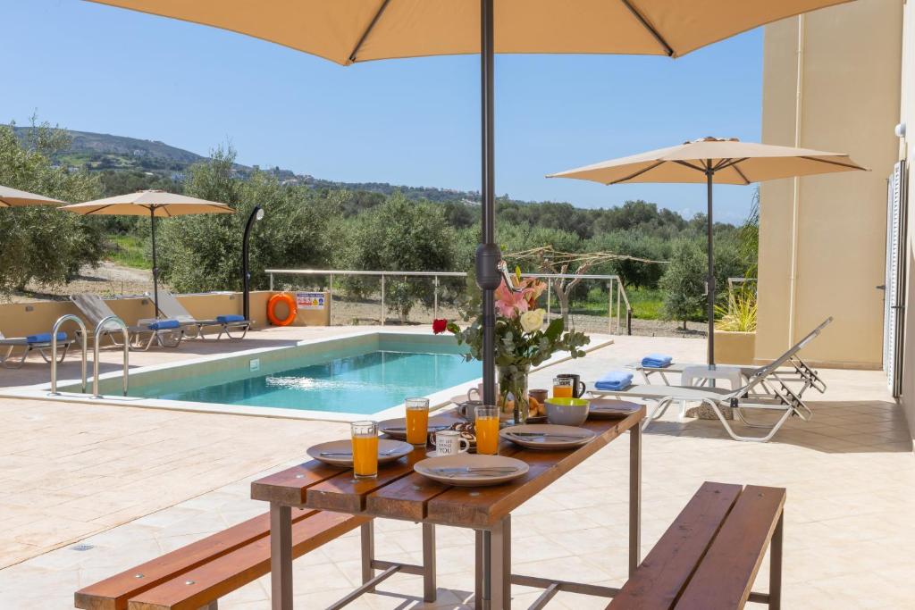 uma mesa com pratos de comida ao lado de uma piscina em Villa Olga em Ayía Paraskeví