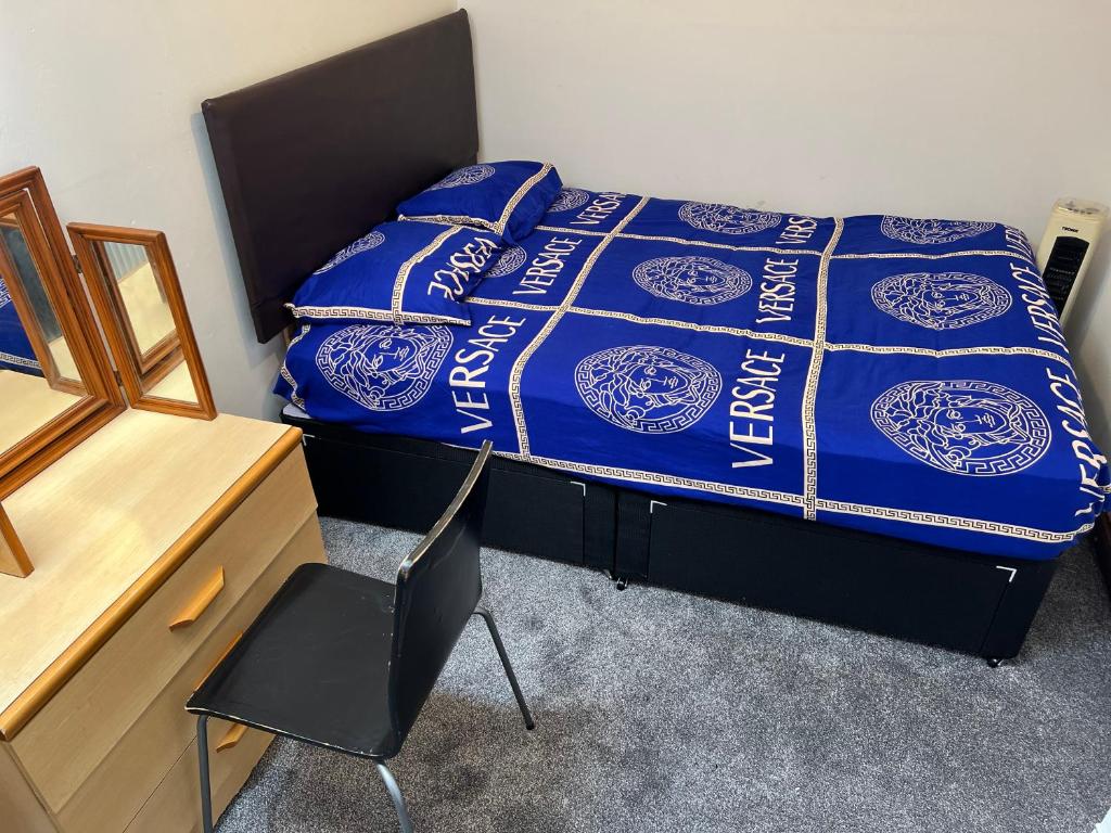 a bedroom with a bed with a blue comforter and a chair at Hastings street in Luton