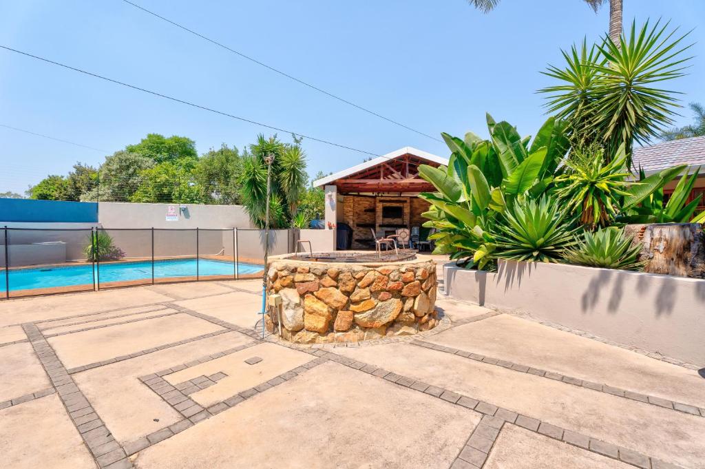 a backyard with a stone fountain and a swimming pool at The Bosau Guest House in Pretoria