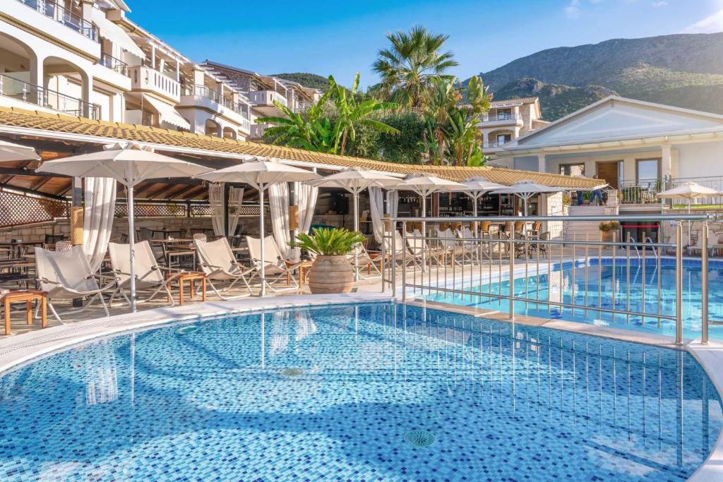 a pool at a hotel with chairs and umbrellas at Adams Hotel in Parga