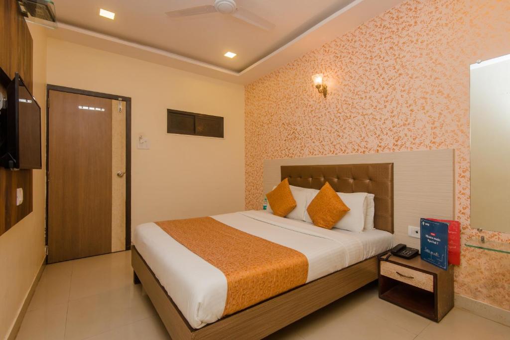 Hotel Golden Nest Near Chhatrapati Shivaji International Airport في مومباي: غرفة نوم بسرير كبير في غرفة
