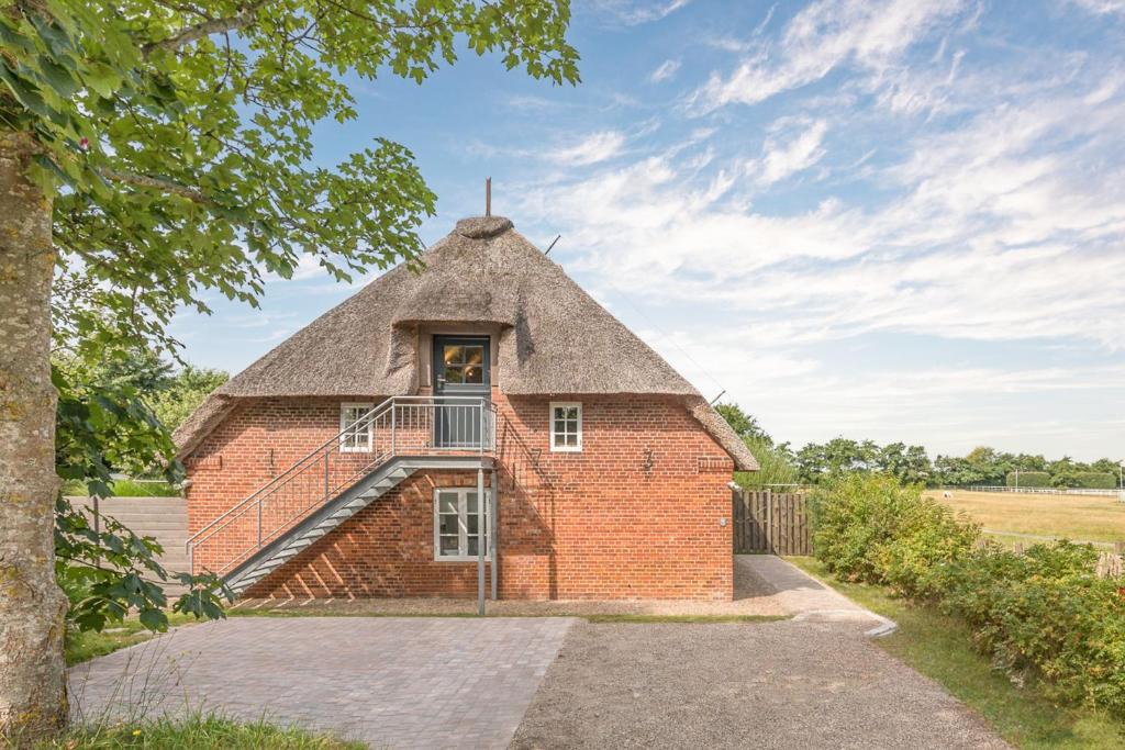 a brick building with a thatched roof at Beach-Loft in Wobbenbüll