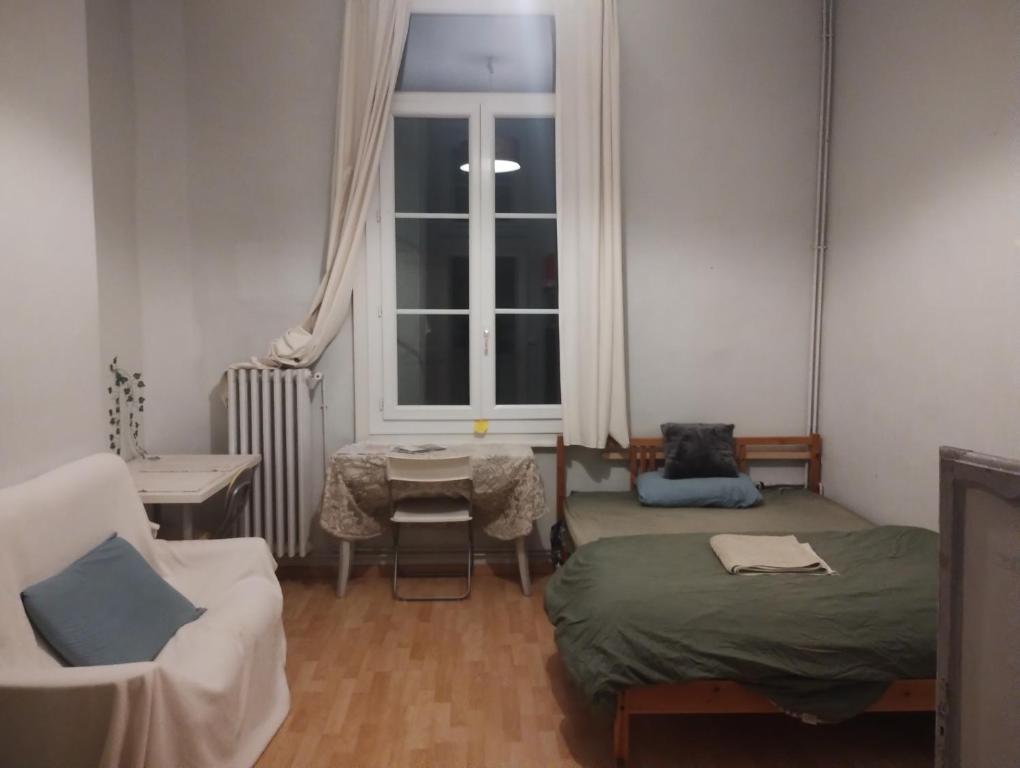 um quarto com duas camas e uma cadeira e uma janela em Cozy Roomy em Montpellier