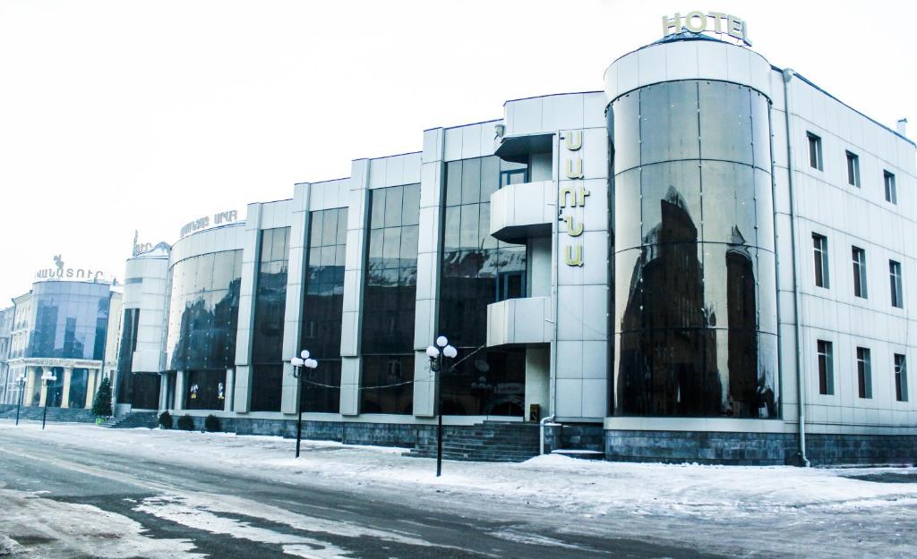 a large white building on a snowy street at Vanatur Hotel in Gyumri