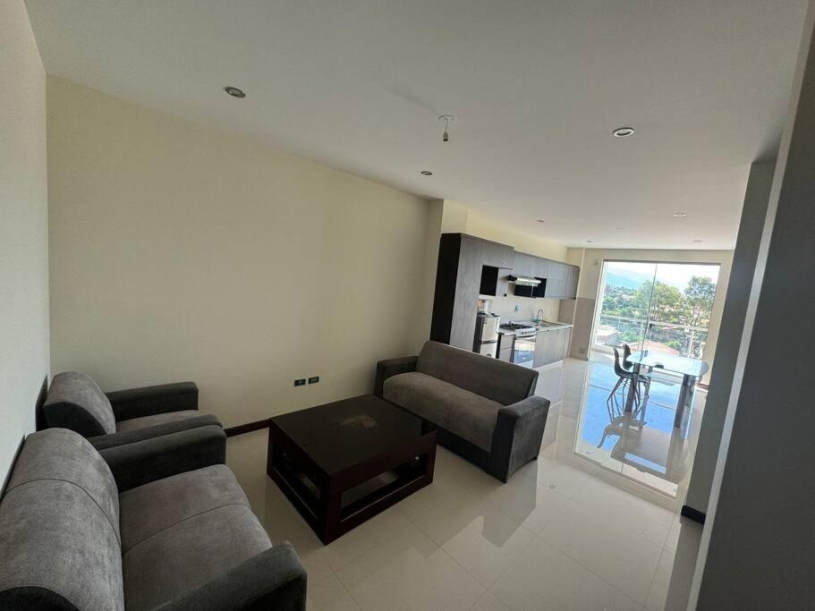 een woonkamer met een bank, 2 stoelen en een tafel bij apartamento completo in Cochabamba