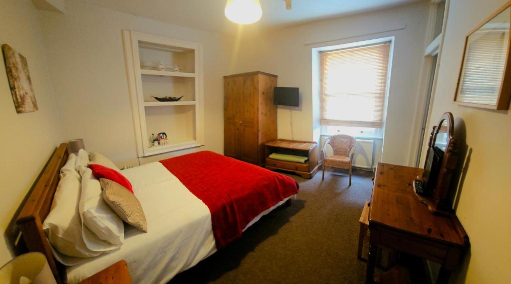 a bedroom with a bed and a desk and a television at The Shrubbery Hotel in Shepton Mallet