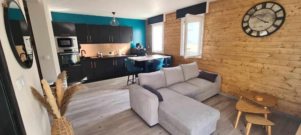 uma sala de estar com um sofá e um relógio na parede em Appartement joli et spacieux em Vitry-le-François