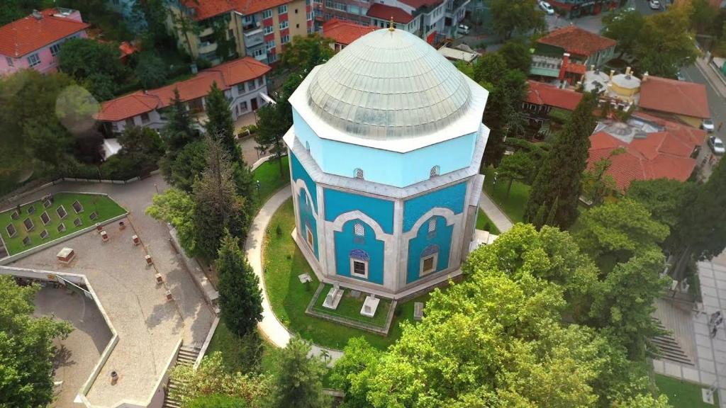 a blue building with a white roof in a city at URAZ Suit Otel in Bursa