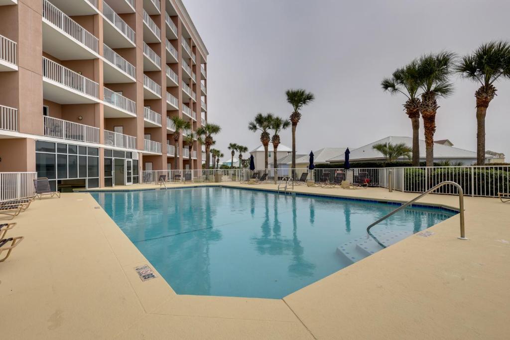 einen Pool vor einem Hotel mit Palmen in der Unterkunft Gulf Shores Condo with Balcony 2 Mi to Fort Morgan! in Gulf Shores