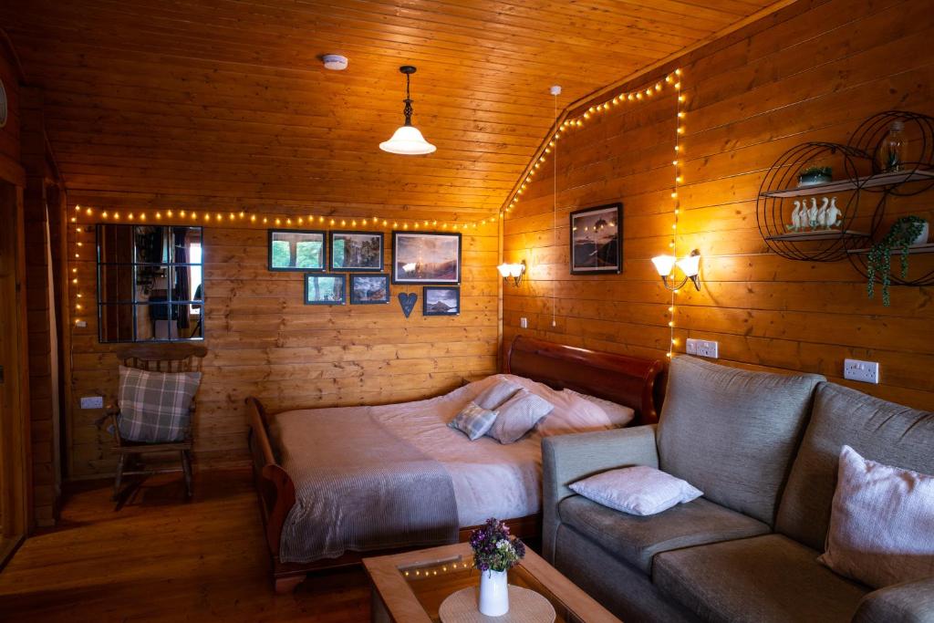 a living room with a bed and a couch at Cherry Cabin - Little Log Cabin in Wales in Bettws Cedewain
