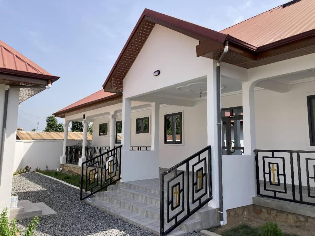 ein weißes Haus mit einem Tor und einer Treppe in der Unterkunft Villa Nova Lodge in Sogakofe