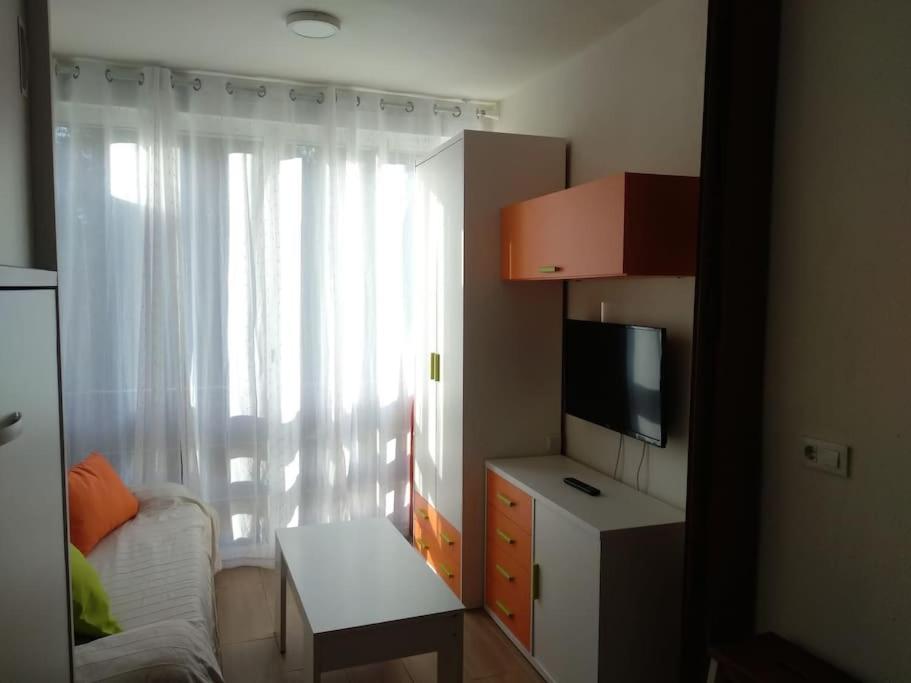 Cette petite chambre comprend un lit, une télévision et une fenêtre. dans l'établissement Estudio con acceso privado y directo a la Playa, à Isla Cristina