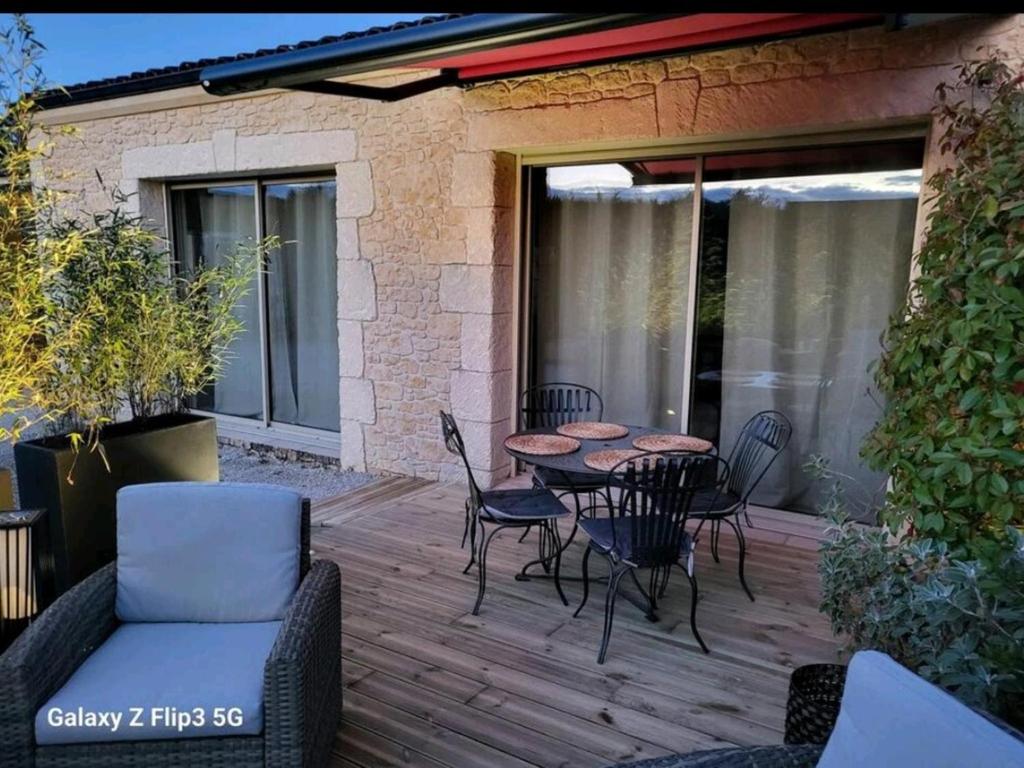 eine Terrasse mit Tisch und Stühlen auf einem Deck in der Unterkunft Maison Cloé in Turnac