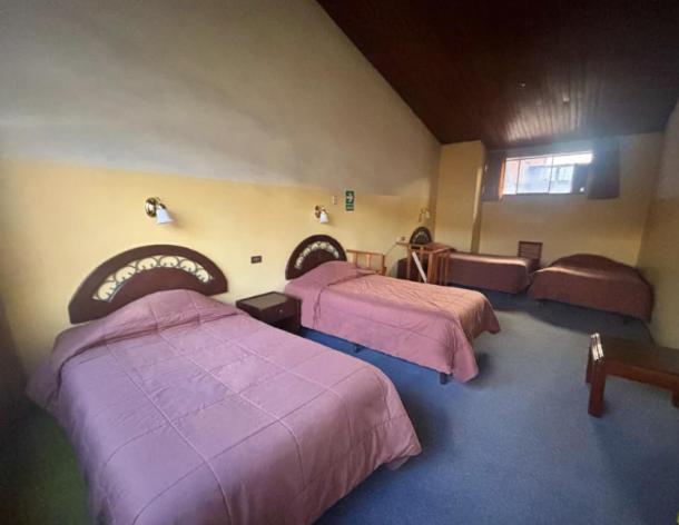 3 camas en una habitación con mantas moradas en Hotel Los Portales en Huaraz