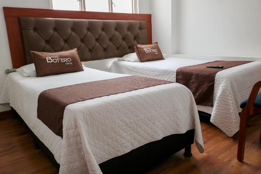 - une chambre avec 2 lits avec des draps blancs et bruns dans l'établissement Hotel Casa Botero 101, à Bogotá