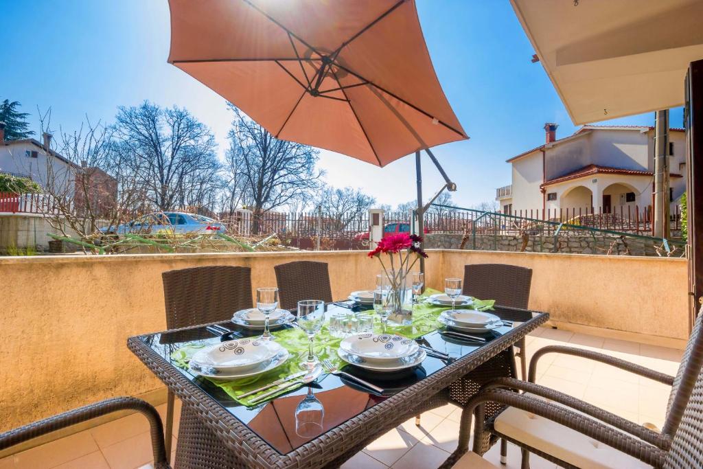 a table on a balcony with an umbrella at Apartment near Opatija in Kastav