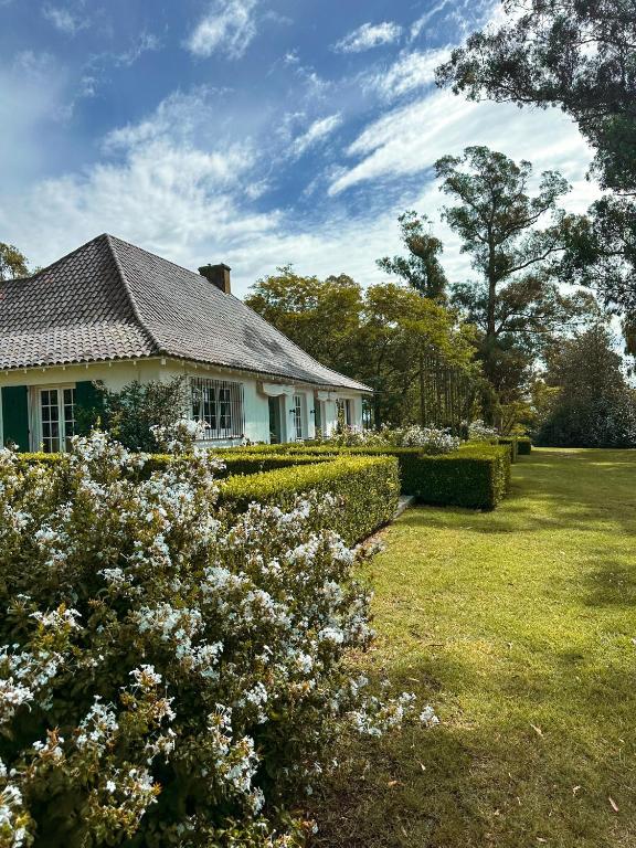 a white house with flowers in the yard at Estancia Ave María in Tandil