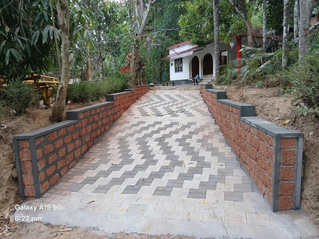 a brick wall and a walkway in front of a house at White Rose in Chegāt