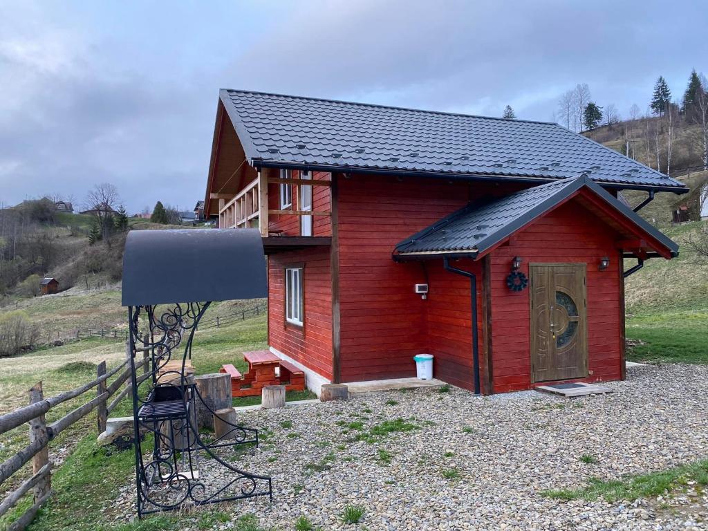 una pequeña casa roja con techo negro en Шпінь 3 en Vorokhta