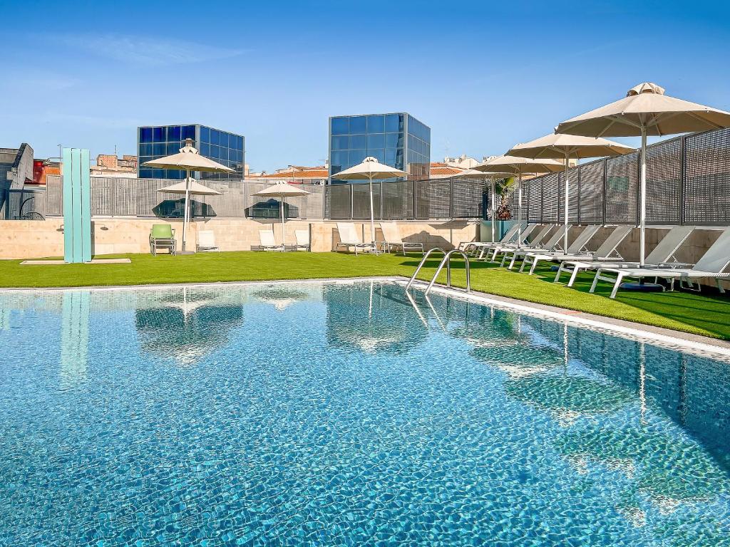 a large swimming pool with umbrellas in a city at Occidental Murcia Agalia in Murcia