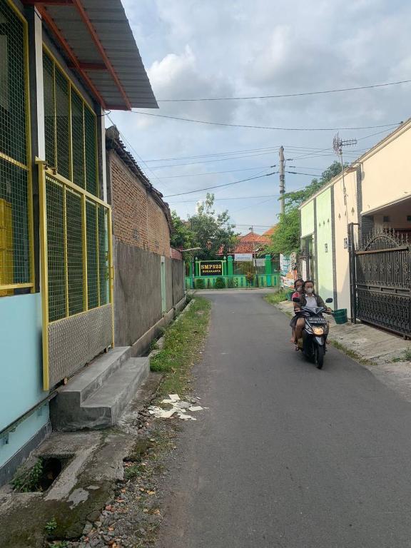 Duas crianças estão a andar de moto numa rua. em LUCKY GUEST HOUSE SOLO em Kadipiro