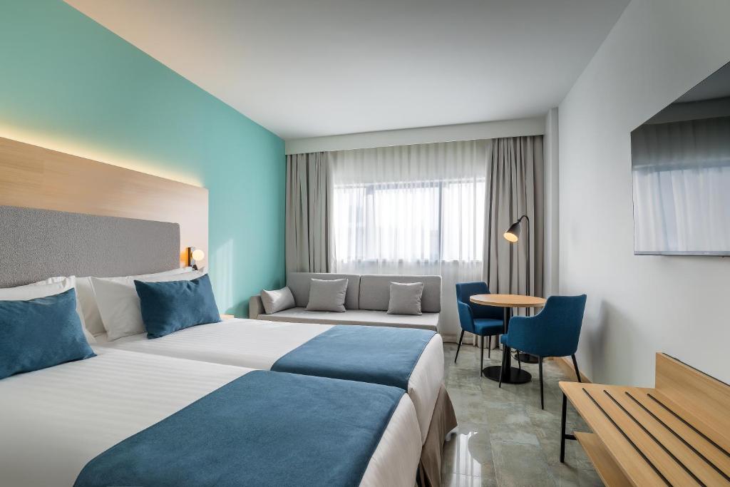ムルシアにあるOccidental Murcia Agaliaのベッド2台とテーブルが備わるホテルルームです。
