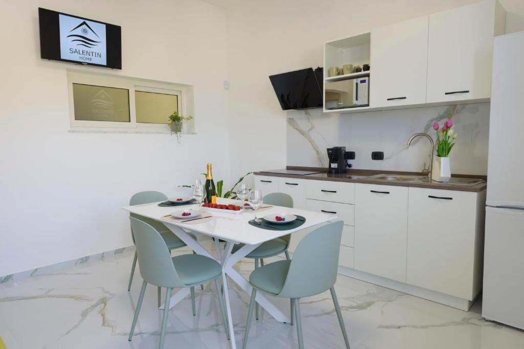 eine weiße Küche mit einem weißen Tisch und Stühlen in der Unterkunft Salentin Home - WindRelax in San Pietro in Bevagna